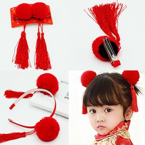 Détail des pinces à cheveux à pompon rouge et du bandeau à glands pour la coiffure d'enfant