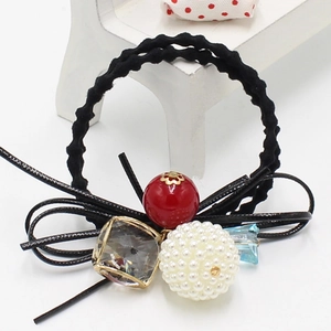 Gros plan sur élastique cheveux noir avec perle rouge, perle blanche et cristal bleu