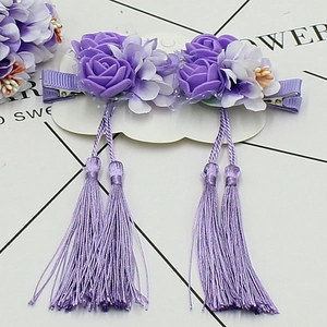 Détail de pinces à cheveux fleurs mauves avec franges sur une carte en nuage