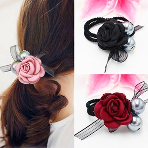 Détail d'élastiques à fleurs avec roses en tissu et perles en rose, noir et rouge