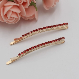 Ensemble de barrettes dorées avec strass rouges sur fond blanc décoré de roses roses