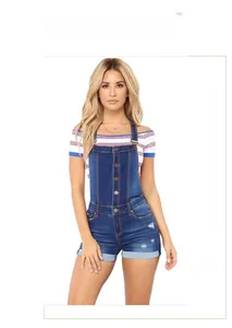 Dettaglio di salopette in denim a vita alta con bottoni metallici e trama strappata