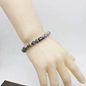 Macro shot of a beaded bracelet with grey marble textures on a model wrist