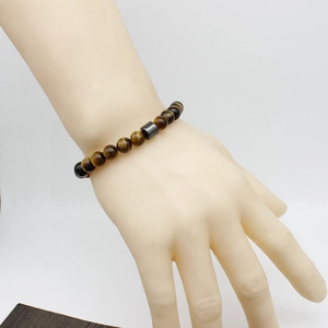 Detail of yellow tiger eye stone bead bracelet with hematite charm on a model's wrist
