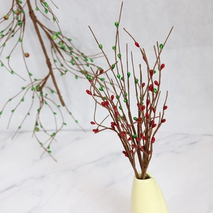 Artificial red and green berry branch in a yellow vase for Christmas DIY home decor