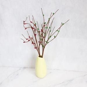 Close-up of artificial red berries in a yellow ceramic vase for indoor decoration