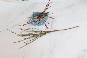 Detailed close-up of artificial red and green berry stems for Christmas DIY decor