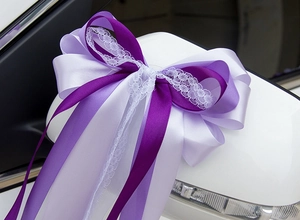 Détail d'un nœud en ruban violet avec dentelle blanche sur le rétroviseur de voiture