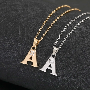 Minimalist gold and silver letter A necklaces with zircon inlays on black surface