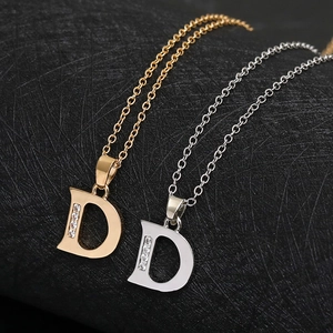 Detail showing gold and silver letter D necklaces with cubic zirconia on a black texture