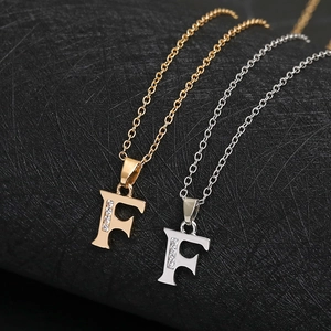 Macro view of gold and silver letter F pendants with tiny crystals on black texture