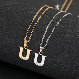 Detailed macro view of U-letter pendant with four inlaid rhinestones in gold and silver