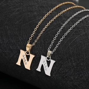Close-up of gold and silver letter N pendant necklaces with sparkling zircon inlay
