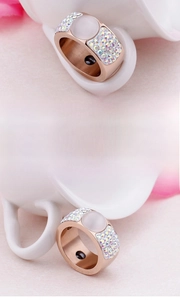 Detail of rose gold magnetic ring featuring a white opal stone and colorful crystals