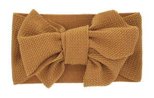 Detailed close-up of caramel waffle knit fabric and large bow on baby headband