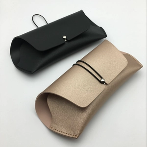 Detail of leather sunglasses cases in black and rose gold with metal button closure