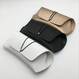 Close-up of leather sunglasses pouches in white, black, and gold with elastic cord closures