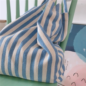 Detailed close-up of blue and white striped canvas tote bag texture on a wooden chair