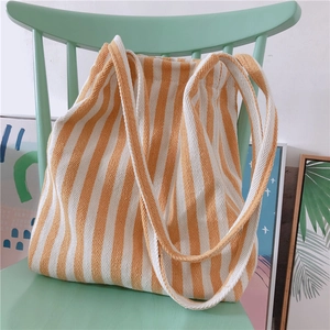 Minimalist yellow and white striped canvas tote bag on a green chair in daily setting