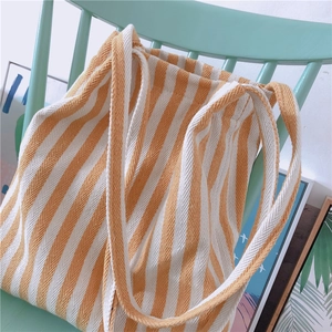 Detail of yellow and white striped thick canvas tote bag draped on a green chair