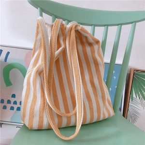 Detail of orange and white striped canvas tote bag hanging on a green wooden chair