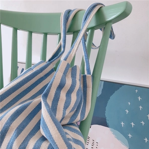 Detailed texture of blue and white striped canvas tote bag on a green wooden chair