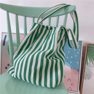 Vertical green and white striped canvas tote bag resting on a mint wooden chair