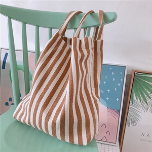 Close-up of brown and white striped canvas tote bag hanging on a green wooden chair