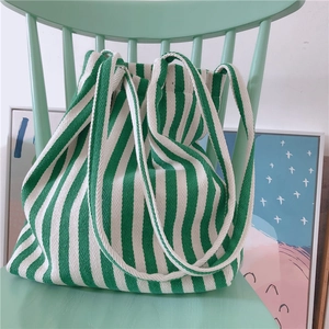 Detailed close-up of thick green and white striped canvas tote bag on a green chair