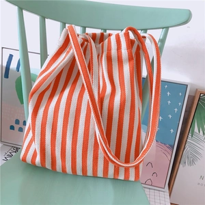 Close-up of orange and white striped canvas tote bag resting on a mint green chair