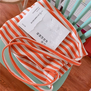 Detail of orange and white striped canvas tote bag on a mint green wooden chair