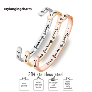 Detailed view of three polished stainless steel C-shaped bracelets in silver gold and rose gold
