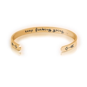 Macro shot of 6mm gold stainless steel C-shape cuff featuring engraved motivational quote
