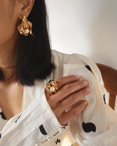 Close-up of gold irregular flower earrings and pearl ring set on model