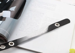 Macro view of black leather belt with silver metal eyelets on a fashion magazine