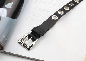 Detail of black punk leather belt with silver grommets and star buckle on a magazine