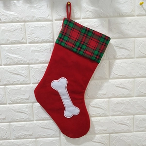 Détail d'une chaussette de Noël rouge avec revers à carreaux verts et broderie d'os