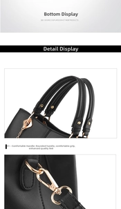 Detail view of black handbag with double handles and golden metallic hook connectors