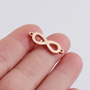 Macro shot of rose gold infinity connector pendant on a fingertip for DIY jewelry