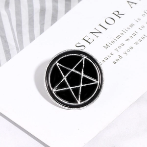 Detail of a vintage punk star enamel brooch pin in black and silver on a textured background
