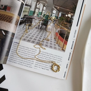 Close-up of a gold wreath necklace on an open magazine with a twisted pendant design