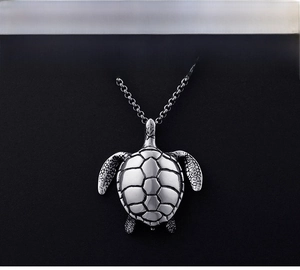Macro detail of vintage silver turtle pendant showing intricate carved shell texture