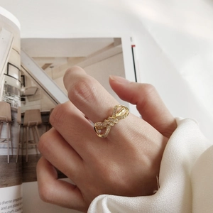 Close-up of a gold bow ring with sparkling zircons worn by a model in a lifestyle setting