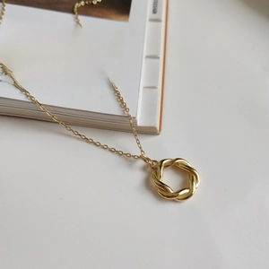 Elegant 925 sterling silver wreath necklace in gold finish on a minimalist book background