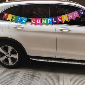 Colorful Feliz Cumpleaños birthday banner hanging on a white SUV side for outdoor party