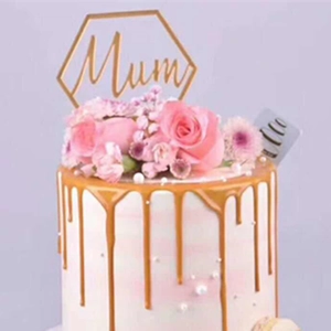 Close-up of golden hexagonal Mum acrylic cake topper with pink roses and gold drips