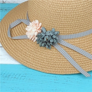 Straw sun hat with floral ribbon decoration on rustic wood background for beach vacation