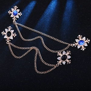 Detail of rose gold cross brooches with blue gemstones and cascading fringe chains