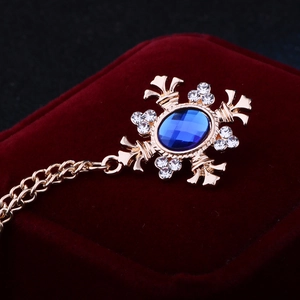 Detail of vintage gold brooch with blue gemstone and rhinestone chain on velvet box