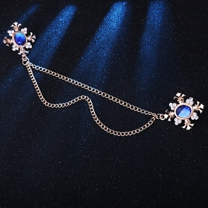 Detailed view of dual vintage gold brooches with blue crystals and tassels on blue base